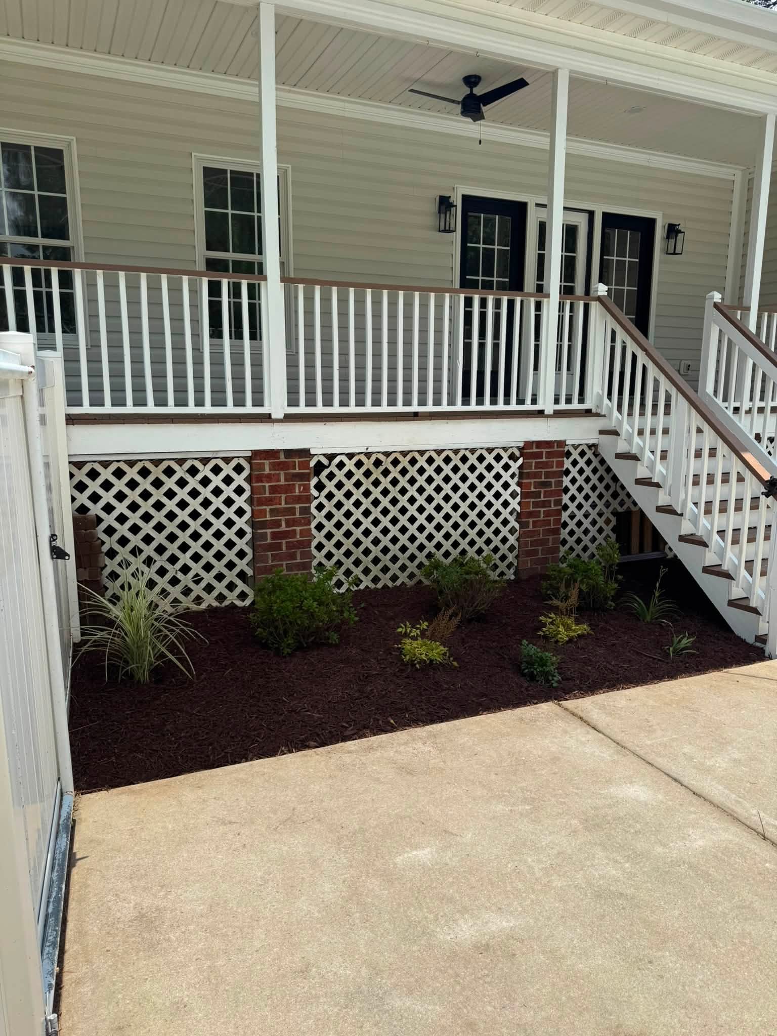 Side yard, after — clean mulched beds and tidy staircase area