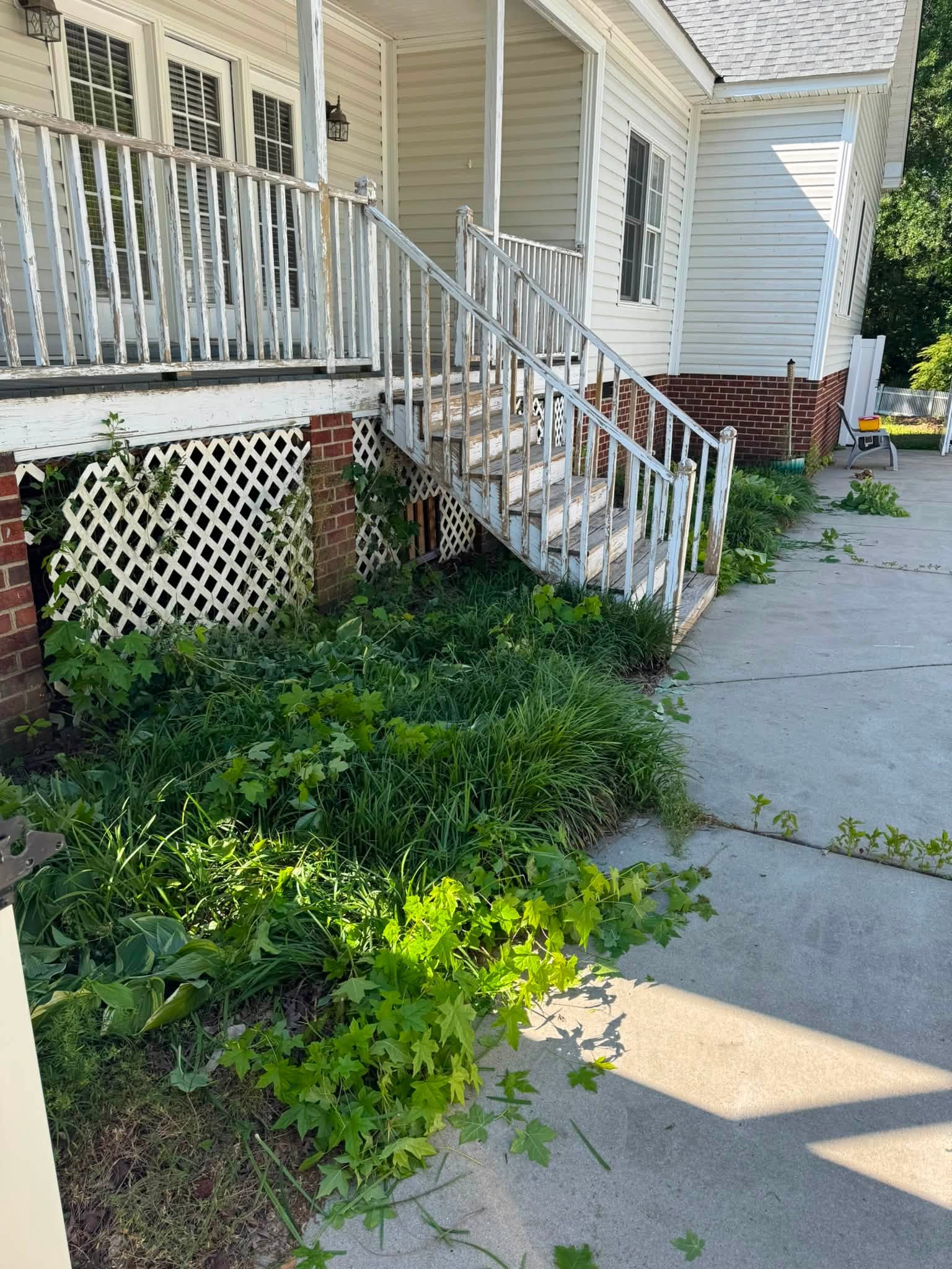 Side yard, before — overgrown bed and cluttered staircase area